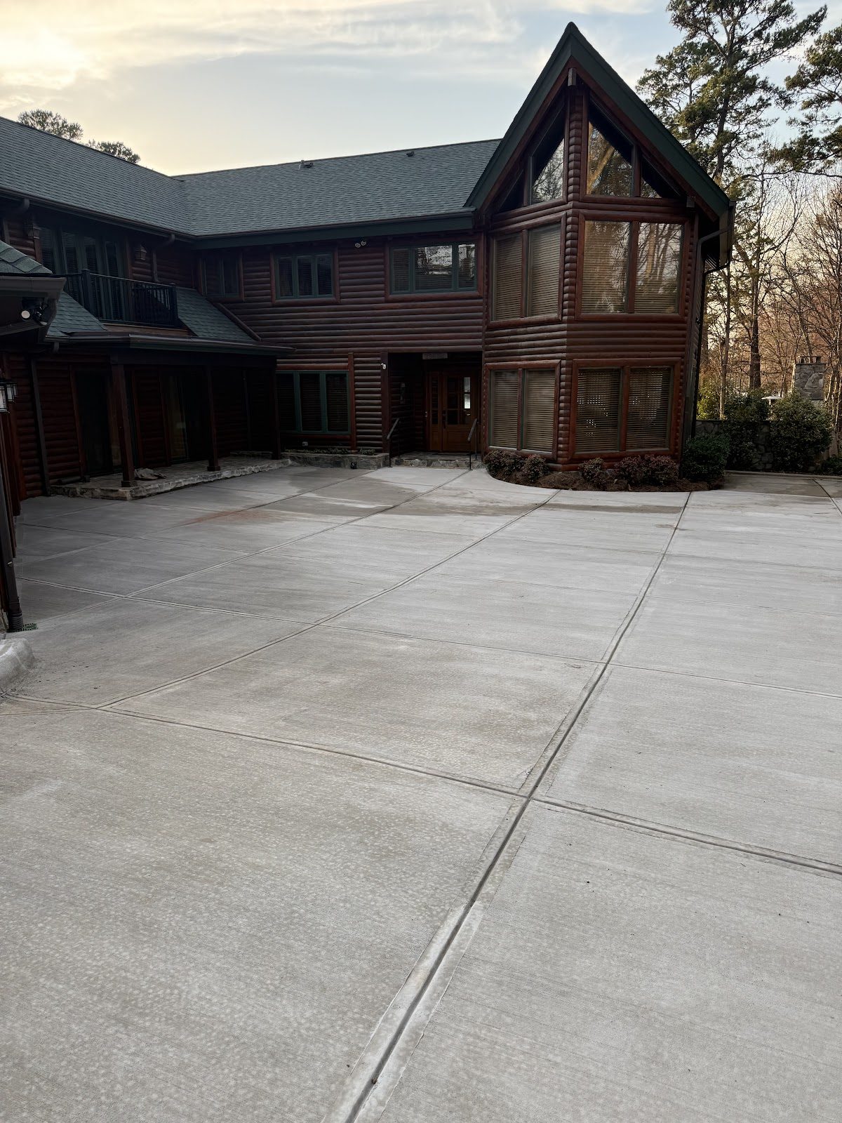 Wide broom-finish concrete driveway at a log estate home