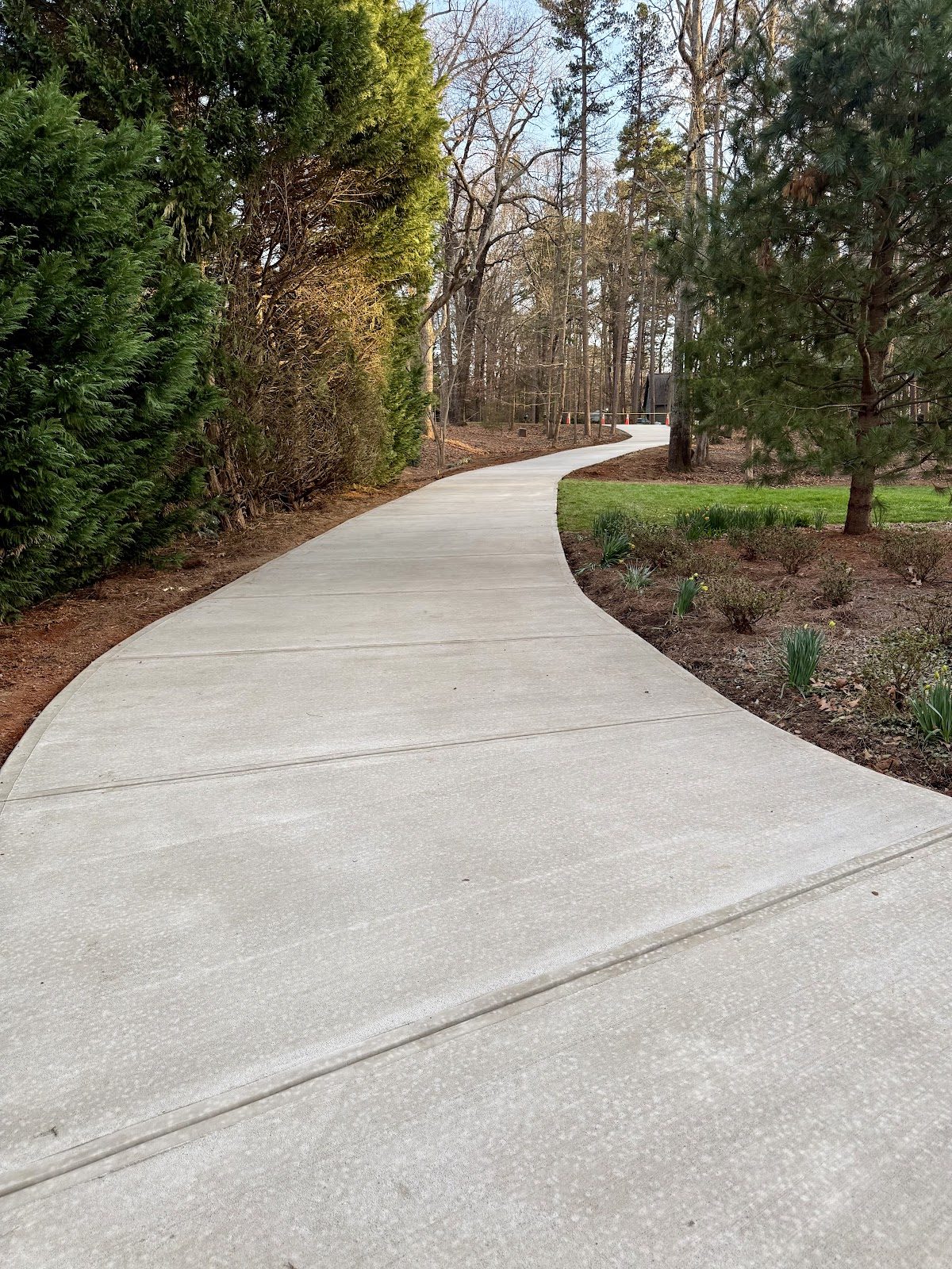 Curved broom-finish concrete driveway on a wooded lot