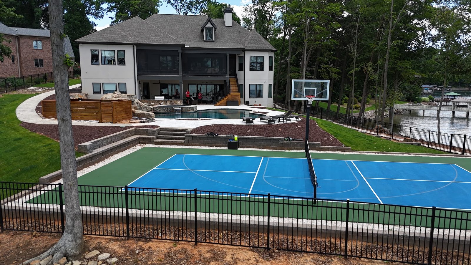 Lakefront pool deck, retaining walls and backyard sport court at a Lake Norman estate